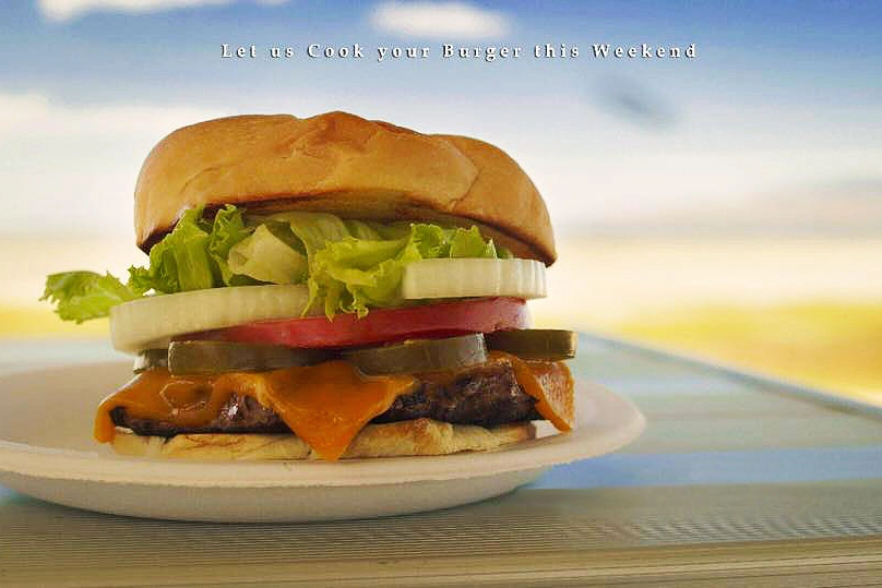Cheeseburger with lettuce, tomato, onion, and pickles on a plate, words above burger.