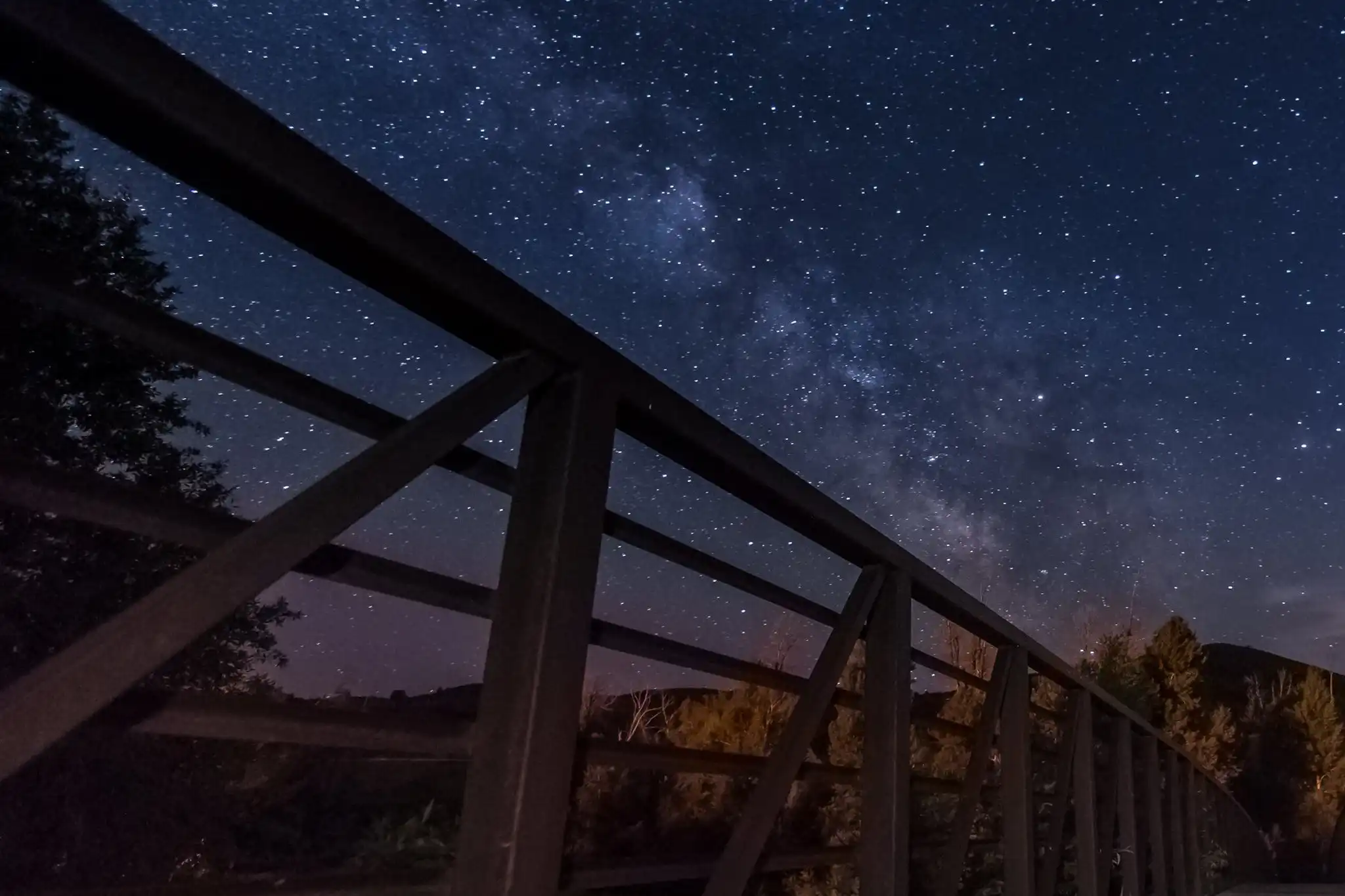 Bridge at night beneath a star-filled sky and visible Milky Way.