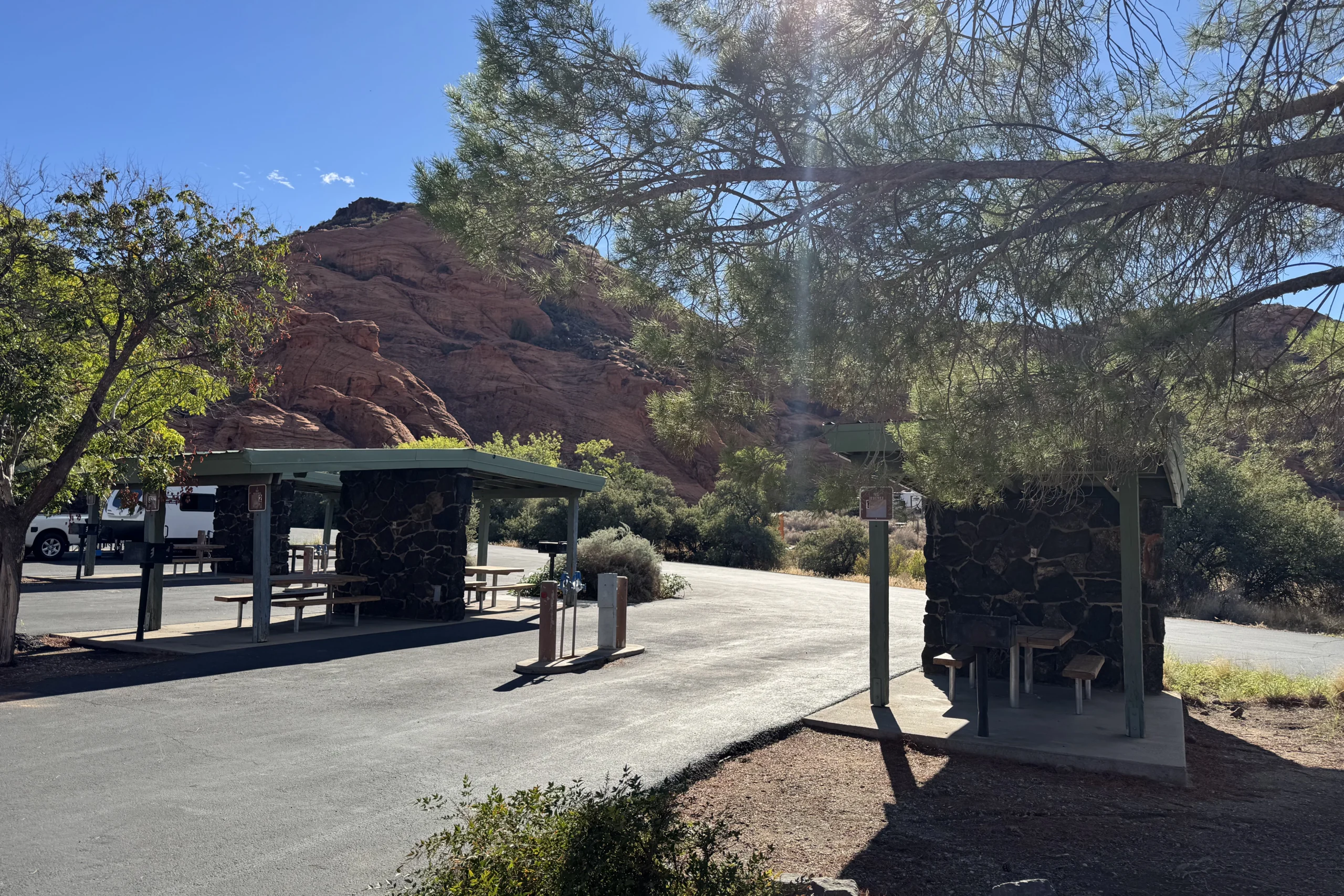 Picnic shelters and water stations near red rock formations under a sunny sky