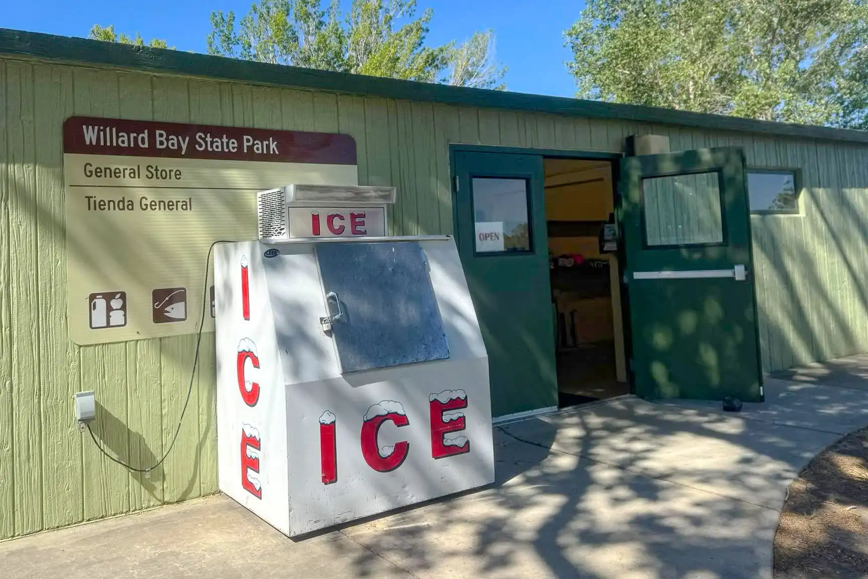 Ice machine outside Willard Bay State Park General Store with open door and sign.
