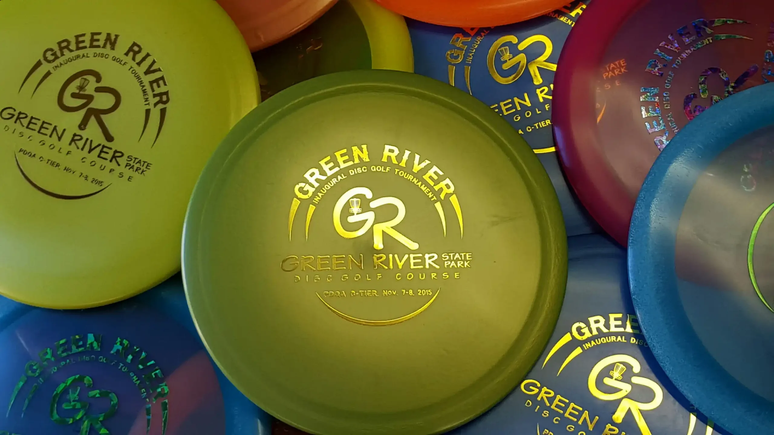 A collection of custom disc golf frisbees that say Green River on them
