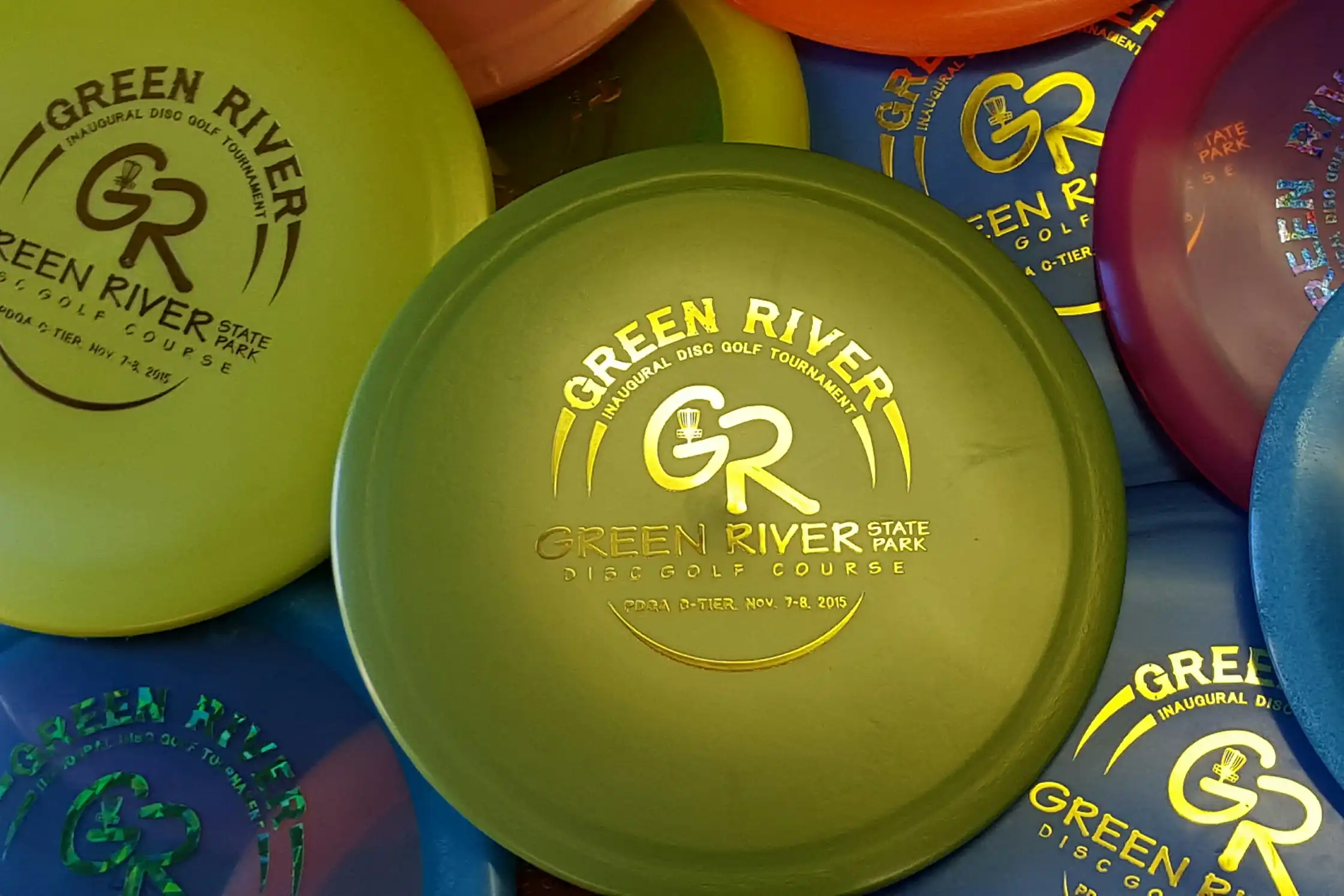 A collection of custom disc golf frisbees that say Green River on them